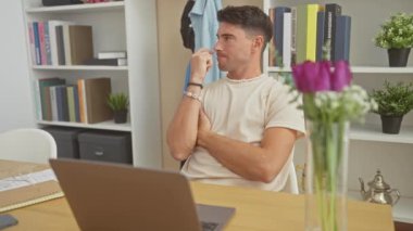 Yakışıklı bir adam evde dizüstü bilgisayar kullanırken düşünüyor ve fikir üretiyor.