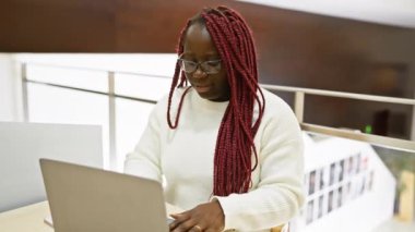 Ofis masasında çalışan, gözlüklü, kederli, siyah bir kadın..