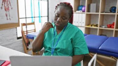Önlüklü Afrikalı kadın fizyoterapi kliniğinde boyun ağrısı çekiyor.