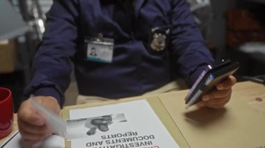 Genç bir İspanyol erkek dedektif polis karakolunda delilleri akıllı telefonuyla inceliyor..
