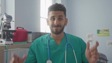 Yeşil önlüklü, steteskoplu, veterinerlik kliniğinde çalışan, etrafı gösteren, klinik ekipmanları görünür olan, sağlık hizmetlerini gösteren genç İspanyol bir adam..