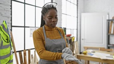 Marangozluk atölyesinde güvenlik gözlüğü takan Afrikalı Amerikalı bir kadın.
