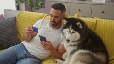 Yakışıklı İspanyol bir adam kredi kartı kullanıyor. Akıllı telefon kullanıyor. Yanında da sadık bir kurt oturuyor..