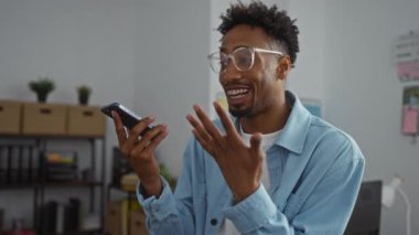 Modern bir ofis ortamında akıllı bir telefonla konuşan yakışıklı genç bir zenci sıradan bir iş ortamı sergiliyor..