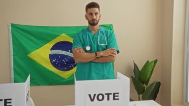 Yeşil üniformalı genç bir İspanyol adam Brezilya bayrağının önünde kapalı bir oylama odasında çapraz kollarla duruyor..