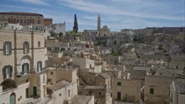 İtalya, Basilicata 'daki tarihi şehrin panoramik bir görüntüsü, açık mavi gökyüzü altında antik mimarisini, taş binalarını ve manzarasını gözler önüne seriyor..