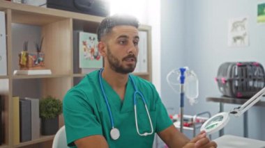 Veterinerlik kliniğinde steteskoplu, yeşil önlüklü genç İspanyol adam, işyerinde odaklanmış ve özenli..