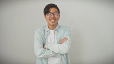 Kesinlikle ışıl ışıl genç Çinli bir adam. Kolları çapraz duran, gözlük takan ve havalı beyaz bir arka planda kazanan bir gülümseme takan kendine güvenen bir Çinli..