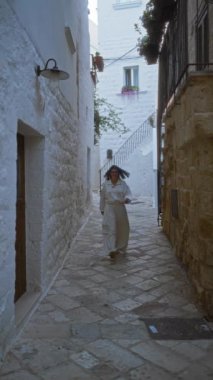 Genç İspanyol bir kadın polignano 'nun büyüleyici sokaklarında yürüyor beyaz taş binalar ve Akdeniz bitkileriyle çevrili bir kısrak Avrupa güzelliğinin özünü yakalıyor..
