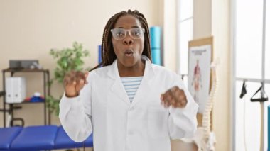 Şaşırmış Afro-Amerikan kadın terapist üniforması, benzersiz bir laboratuvar keşfi karşısında şaşkınlık ve korkuyu gözler önüne seriyor..