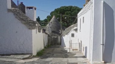 Genç bir İspanyol kadın güneşli bir günde geleneksel beyaz trulli evlerle çevrili İtalya 'nın alberobello sokaklarında yürüyor..