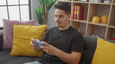 Sakallı genç bir İspanyol, evinin oturma odasında video oyunu oynuyor..