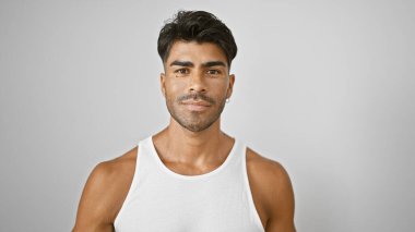 Sakallı yakışıklı İspanyol bir adam beyaz bir bluzla izole edilmiş beyaz bir arkaplana karşı güvenle poz veriyor..