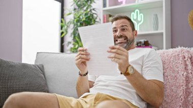 Modern oturma odasında gazete okuyan neşeli, olgun bir adam, şık bir dekorla mutluluğu ve rahatlığı ifade ediyor..