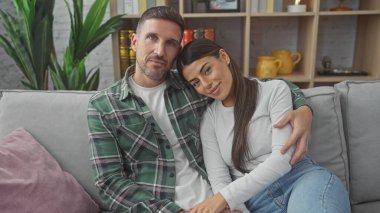 Sevecen İspanyol çift rahat bir oturma odasında kanepede dinleniyor, birbirlerine sevgi ve birliktelik yayıyorlar..