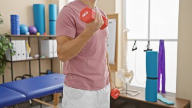 Genç İspanyol bir adam fizik tedavi kliniğinde ağırlık kaldırıyor, sağlık ve sağlık hizmetlerini gösteriyor..