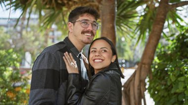 Güneşli bir şehir sokağında kucaklaşan sevgi dolu çift, tropik bir şehir ortamında mutluluk ve aşk saçıyor..