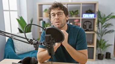 Sakallı genç bir İspanyol, radyo stüdyosunun mikrofonuna konuşuyor..