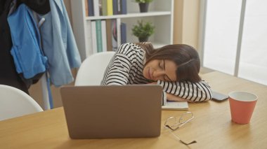 Genç bir İspanyol kadın evinde uyuyor, elinde dizüstü bilgisayar, gözlük ve kırmızı bardakla..