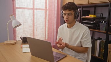 Ofisteki genç İspanyol adam kulaklık ve gözlük takıp video görüşmesine odaklanmış..