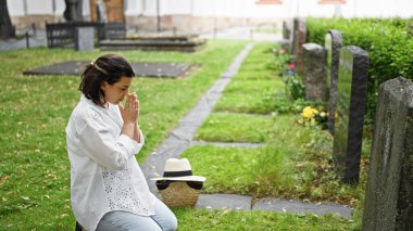 Güzel, genç, İspanyol bir kadın mezarlıkta dua ediyor ve yas tutuyor.
