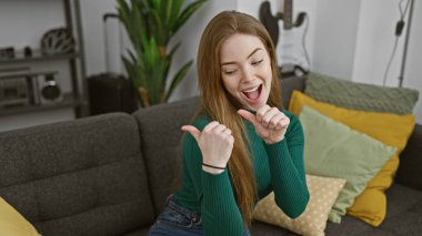 Neşeli, genç, beyaz bir kadın evde başparmaklarıyla göz kırpıyor..