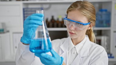 Genç bir kadın bilim adamı laboratuvar ortamında bir kimyasalı inceliyor, araştırma ve sağlık hizmetleri sunuyor..