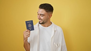 Sarı arka planda Amerikan pasaportuyla gülümseyen yakışıklı bir adam.