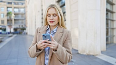 Şehir caddesinde akıllı telefon kullanan şık bir genç kadın..