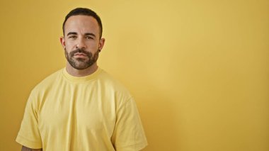 Sakallı genç bir İspanyol 'un portresi, sarı arka planda günlük giysiler giyiyor, modern şehir tarzını somutlaştırıyor..