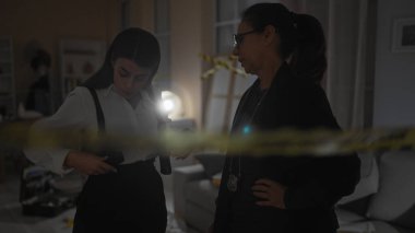 İki kadın dedektif, kapalı bir suç mahallinde kanıtları incelerler. Biri el feneriyle..