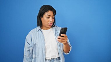 Gizli bir şekilde yakalanan mavi duvara karşı akıllı telefondan mesaj atan İspanyol kadın..