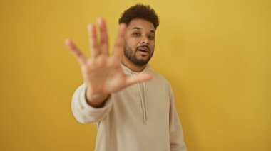 Dört numaralı jesti yapan Afrikalı Amerikalı adam sarı arka planda izole edilmiş..