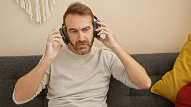 Sakallı, orta yaşlı bir adam oturma odasında kulaklıkla müzik dinlemekten hoşlanır..