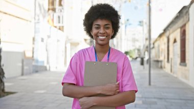 Pembe önlüklü gülümseyen Afro-Amerikan bir kadının portresi..