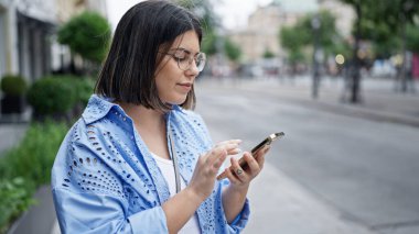 Genç ve güzel İspanyol kadın Viyana sokaklarında akıllı telefon kullanıyor.