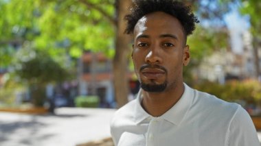 Güneşli bir günde canlı bir şehir parkında sakallı yakışıklı Afro-Amerikalı bir adam..