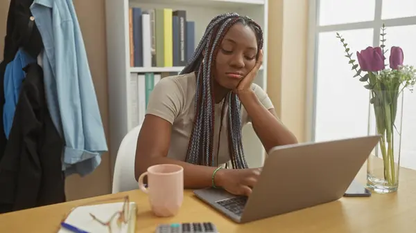 stock image African american woman with braids working on laptop at home, showcasing a cozy indoor portrait setup.