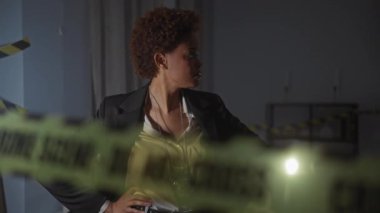 Dedektif kadın, karanlık bir odada el feneriyle bir suç mahallini araştırıyor.