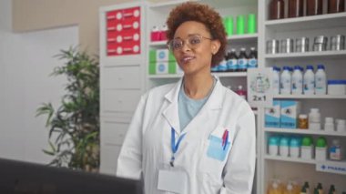Komik afro-amerikan kadın eczacı eczaneye dilini sokuyor, yüzünde komik bir ifade var.