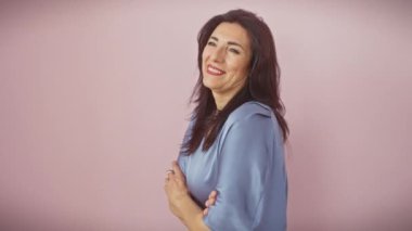 Kendinden emin orta yaşlı İspanyol kadın neşeli bir şekilde güler profilden uzağa bakar doğal bir gülümsemeyle izole edilmiş pembe arka planda..
