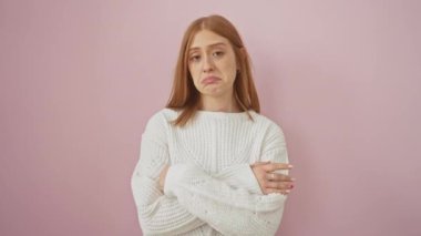 Stresli, kızıl saçlı, kazaklı bir kadın yalnız başına duruyor ve depresyon belirtileri gösteriyor. Endişeli, kızgın pembe bir arka planda acı dolu bir bakışla, sorununu ifade ediyor..