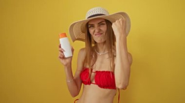 Beyaz tenli kadın güneş kremi çılgınca öfke dolu bağırış çağırış izole edilmiş sarı arka plan, öfkeli sarışın kumsala giden şapkalı kadın çileden çıkıyor.