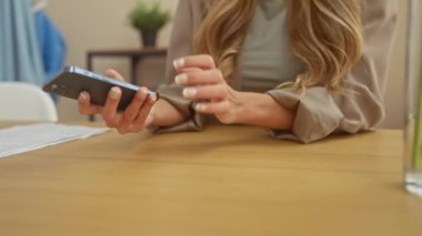 Neşeli genç bir kadın şık oturma odasında cep telefonuyla konuşuyor, rahat ve modern bir yaşam tarzını somutlaştırıyor..