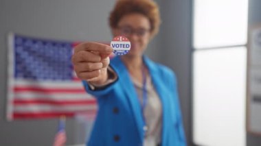 Afro-Amerikalı bir kadın, Amerikan bayrağıyla bir oy verme merkezinde gururla 