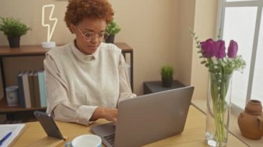 Neşeli Afro-Amerikalı kadın evinde bir masada oturuyor, umut dolu gülümseme ve kapalı gözlerle, batıl inançlar ve pozitif titreşimlerle parmaklarını çaprazlıyor..