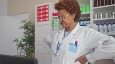 Gergin ve şüpheci, eczacı üniforması giyen üzgün bir Afrikalı Amerikalı kadın eczanedeki bir sorundan dolayı kaşlarını çatıyor. Onun olumsuz ifadesi derin bir endişe işareti..