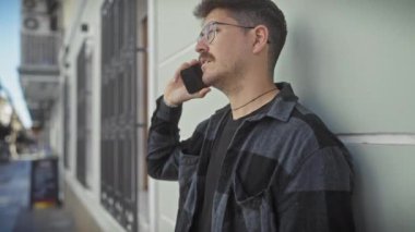 Latin kökenli genç bir adam şehir caddesinde akıllı bir telefonla konuşuyor, şehir bağlantısını ve günlük yaşam tarzını aktarıyor..