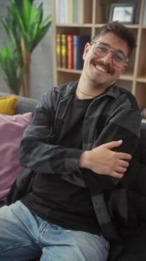Havalı, genç İspanyol bir adam, özgüven ve başarının portresi, kanepede oturuyor, doğal, dostane bir gülümsemeyle. Gözlük takıyor, kollarını kavuşturup mutlu bir şekilde evinden kameraya bakıyor.