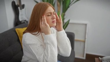 Stresli genç bir kadın evde, şiddetli migren ağrısı çekiyor. Kızıl saçlı, kazak giyiyor, çaresizlik içinde başını tutuyor. Hayatın gürültülü endişelerinden derinden etkilenmiş..